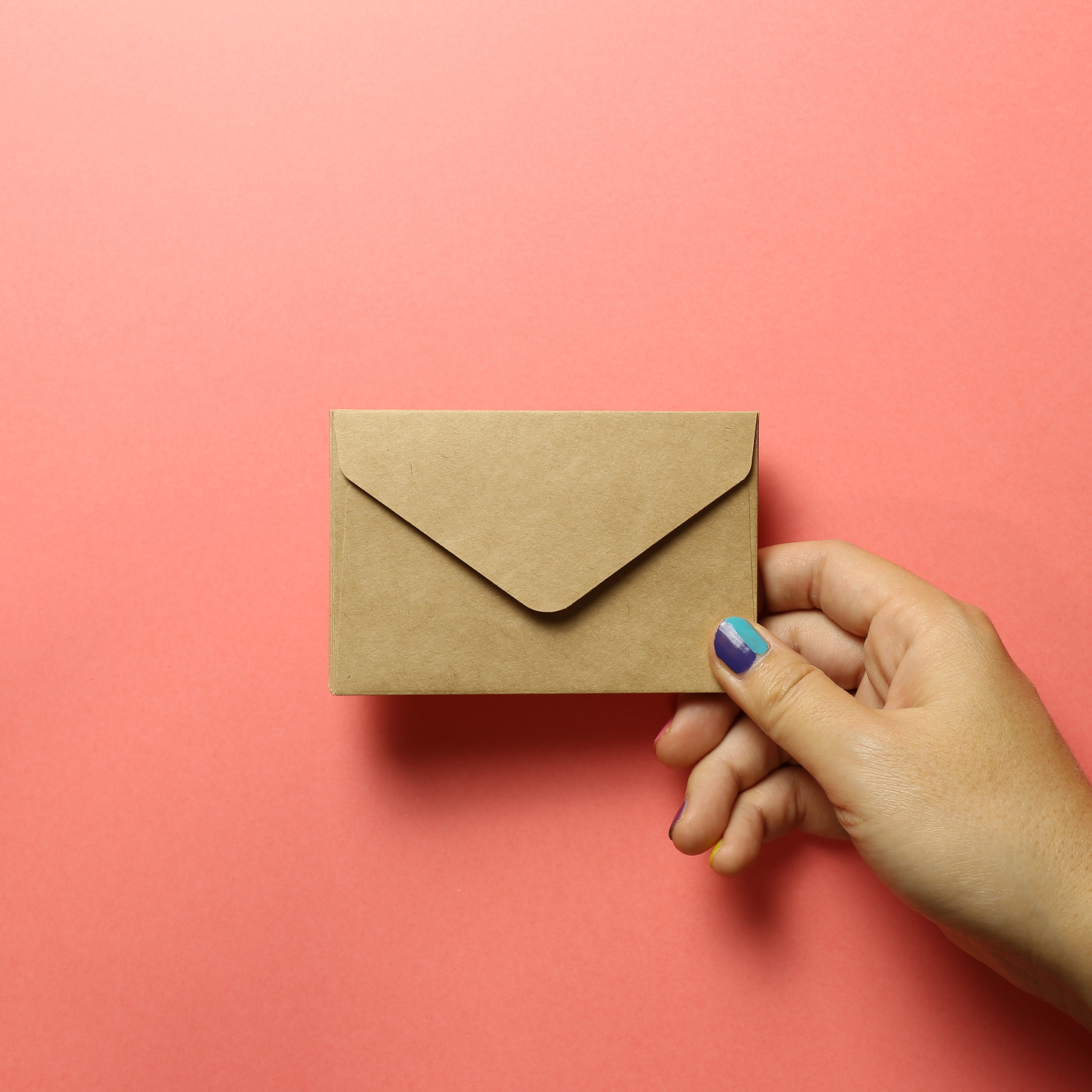 Kraft brown paper envelope with hand on pink background